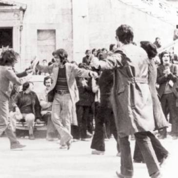 Προαύλιο Πολυτεχνείου, μεσημέρι πρώτης μέρας της κατάληψης, Τετάρτη 15 Νοεμβρίου 1973. Φοιτητές χορεύουν και τραγουδάνε και χτυπάνε παλαμάκια.