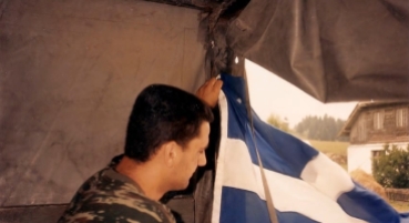 Βοσνία, 1995. Διακρίνεται ένας Ελληνας εθελοντής της ΕΕΦ, ο Κωνσταντίνος Καλτσούνης (βαμμένος χρυσαβγίτης που λέγεται ότι αυτοκτόνησε τέλη Μαρτίου 2016 λόγω οικονομικών προβλημάτων) με ελληνική σημαία σε αντίσκηνο.
